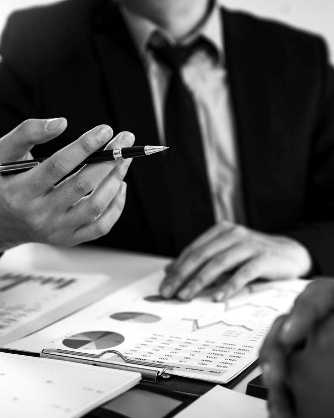 A financial advisor and a client reviewing a portfolio report together, black and white