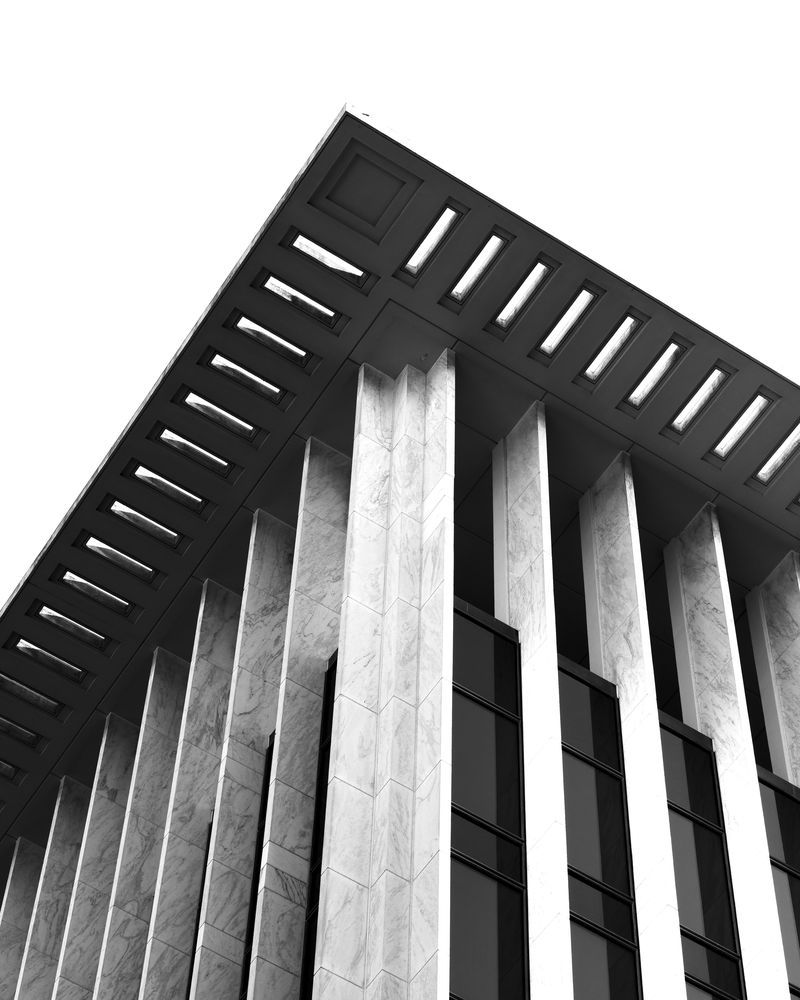 The corner of a marble-columned office tower against a white sky