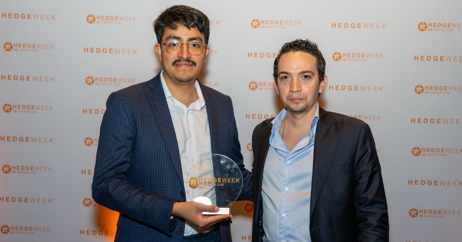 Two members of the Fintela team, co-founder Manuel Padrón on the right, holding the Hedgeweek US Awards 2026 trophy in front of the Hedgeweek backdrop in New York.